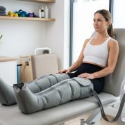Femme utilisant des bottes de compression pneumatique pour la récupération musculaire dans une clinique de physiothérapie moderne