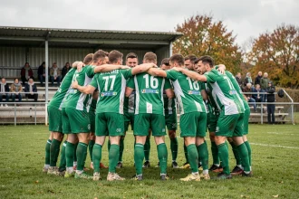 Équipe de football amateur du district de la Sarthe en cercle avant le coup d'envoi sur un terrain herbeux en automne